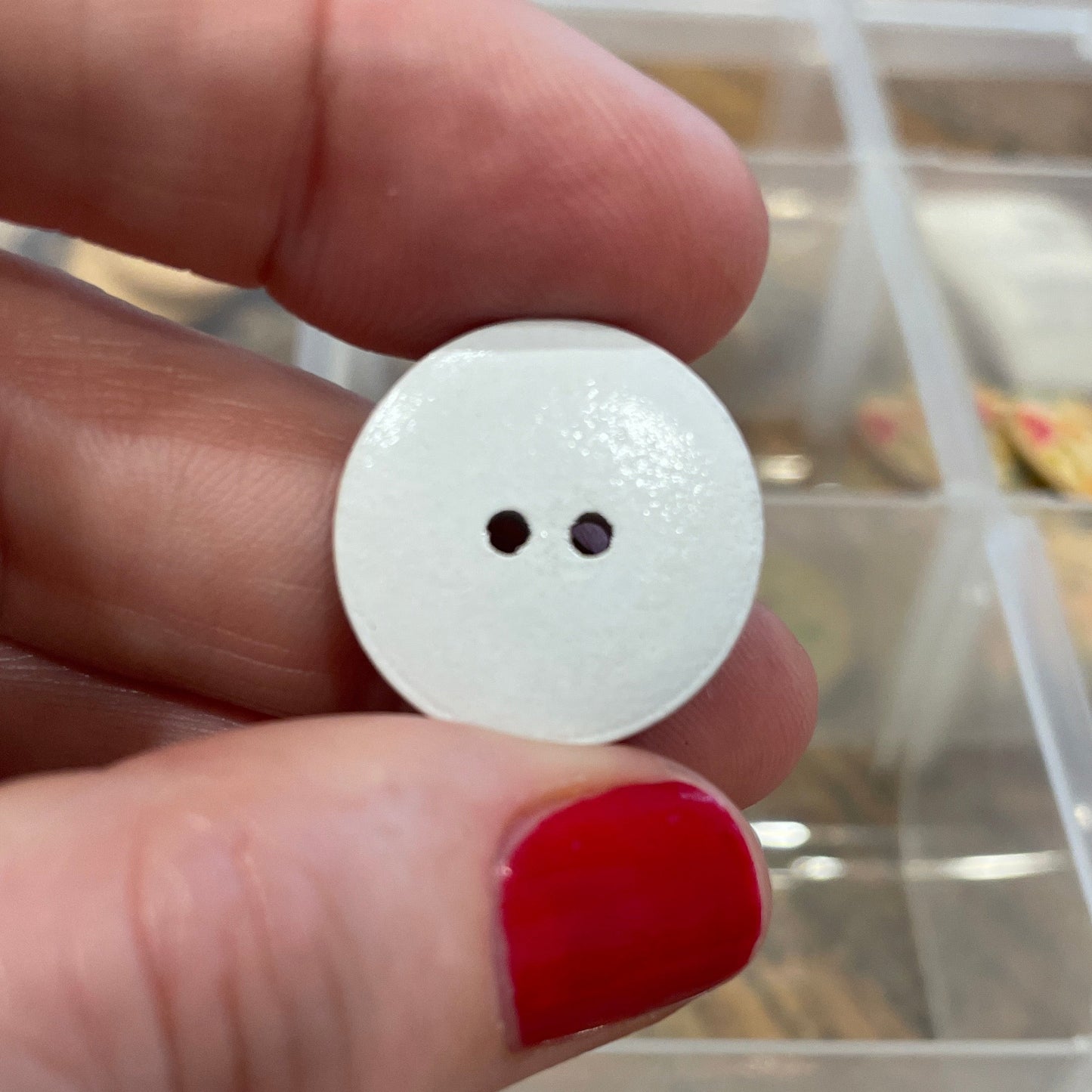 White button held between fingers with a blurred background