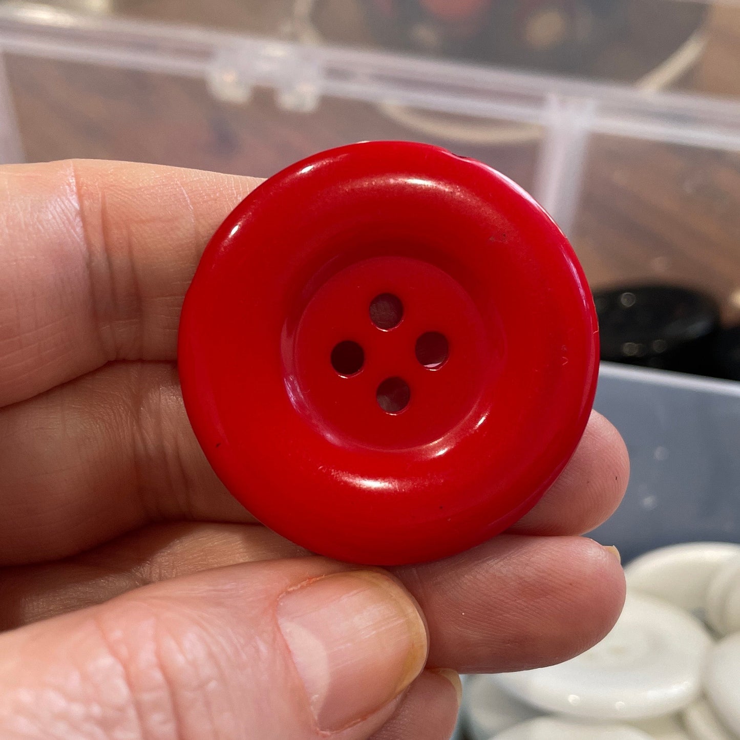 Red button held in a hand with a blurred background