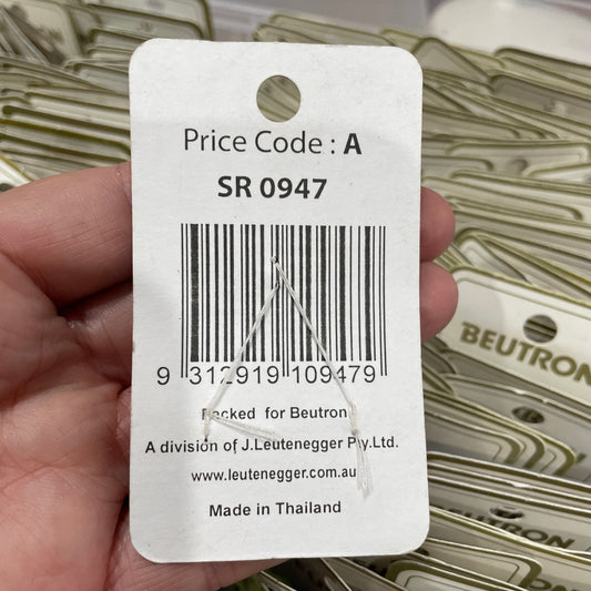 Hand holding a product tag with a barcode and text, with a blurred background of similar tags.