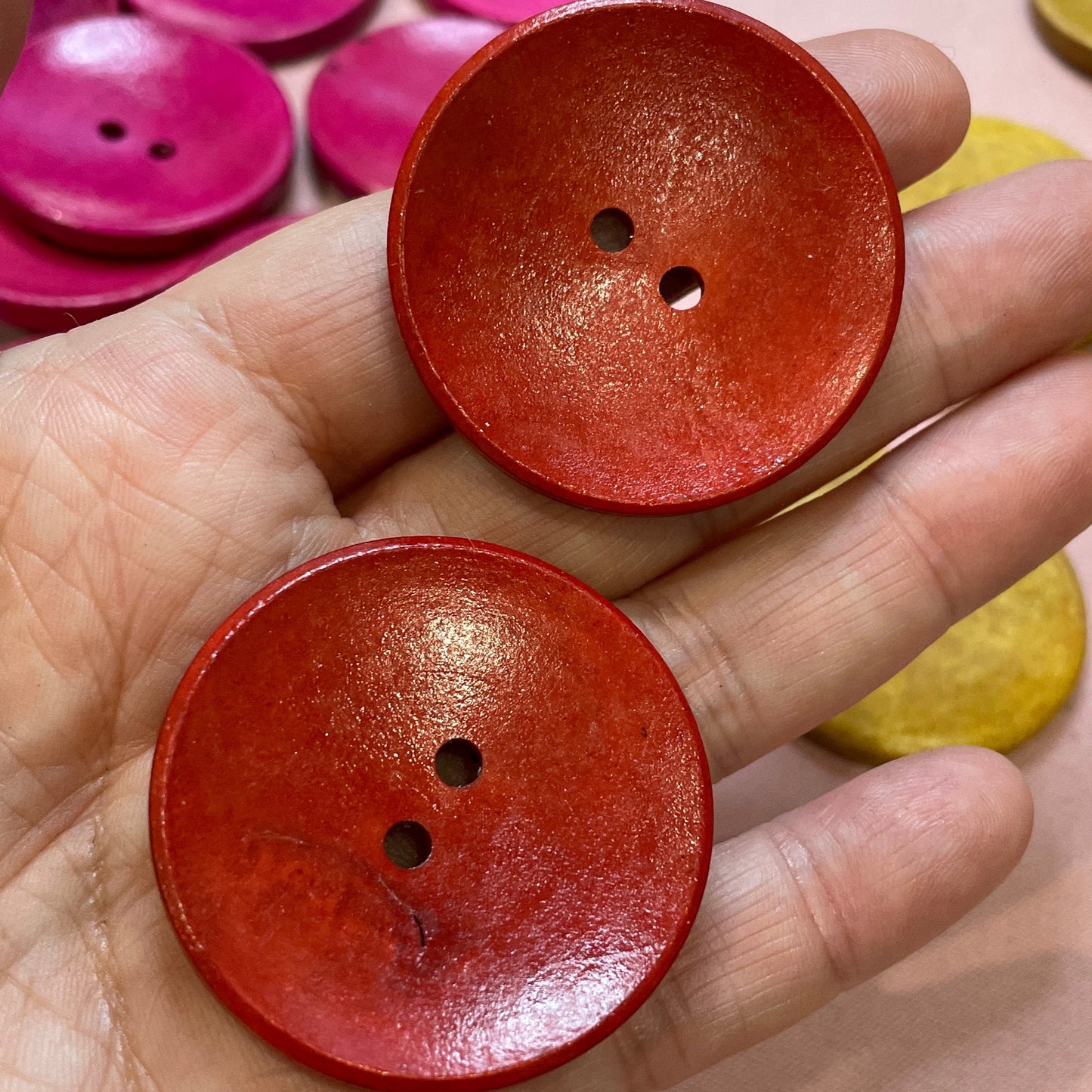Hand holding two red buttons with a background of colorful buttons