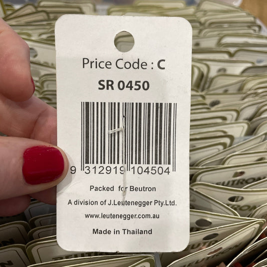 Close-up of a price tag with a barcode and text, held by a hand with red nail polish.