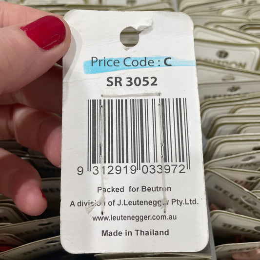 Bar code label held by a hand with red nail polish, with a blurred background of similar labels.