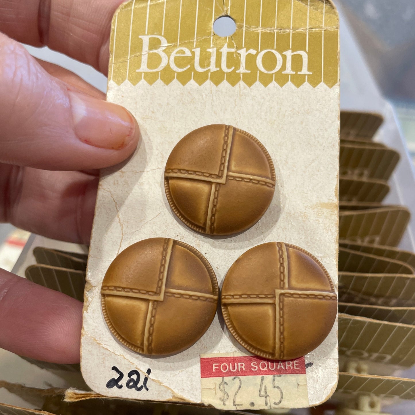 Packaged leather look buttons held by a hand with a blurred background