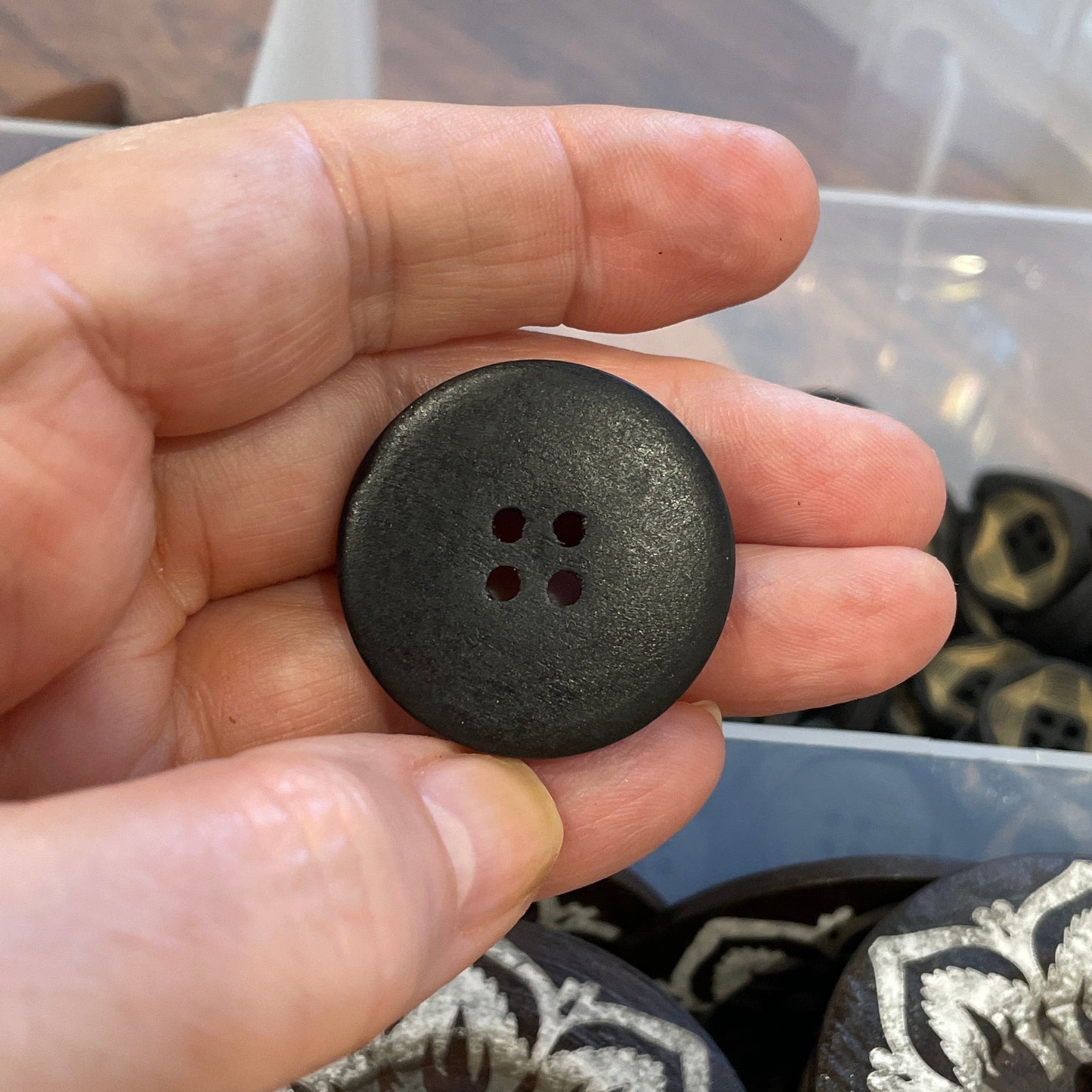 Hand holding a black button with decorative patterns in the background
