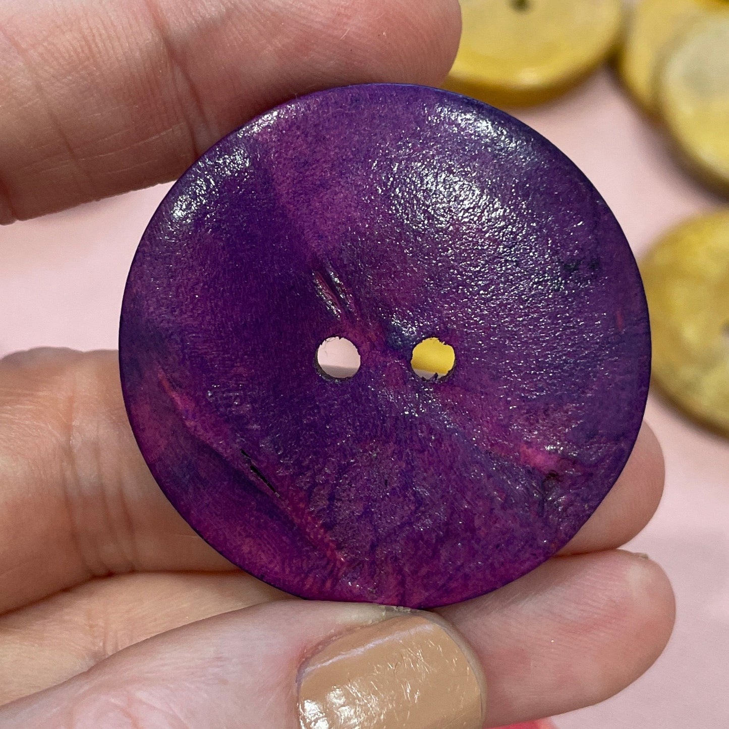 Hand holding a purple button with other colorful buttons in the background