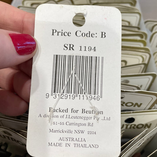 Close-up of a price tag with a barcode held by a hand, surrounded by similar tags.