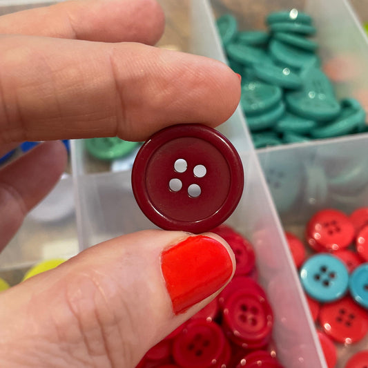 Person holding a red button with button collection in the background