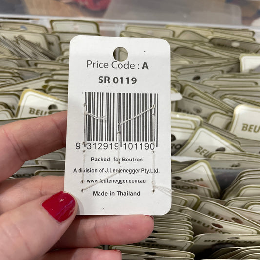Hand holding a price tag with a barcode and text, with a background of similar tags.