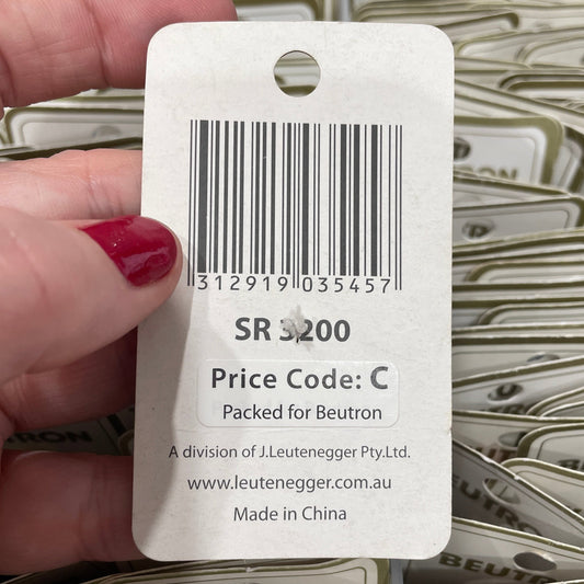 Hand holding a white label with a barcode and text, with a background of similar labels.
