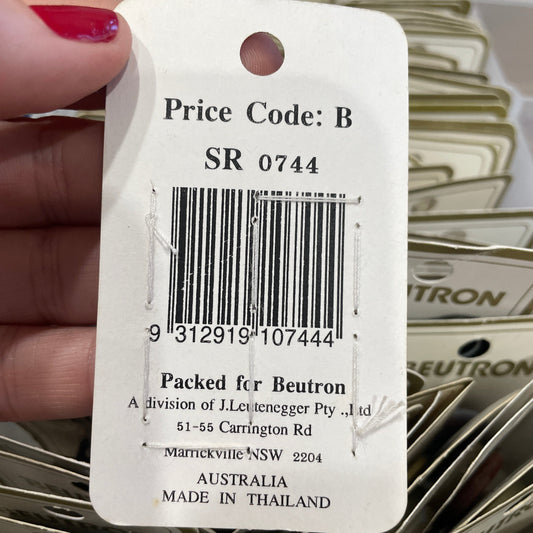 Close-up of a product tag with a barcode and text, held by a hand.