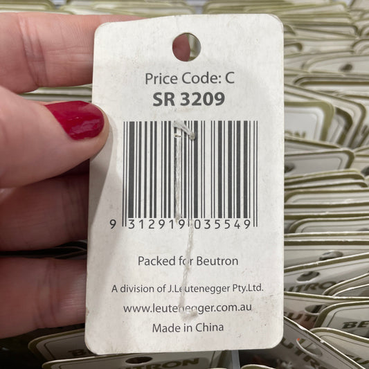 Close-up of a hand holding a product tag with a barcode and text, with more tags in the background.