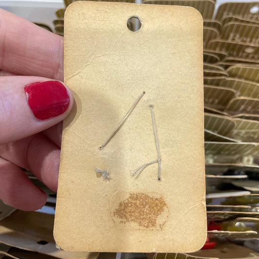 Card held by a hand with red nail polish, with a blurred background of similar cards.