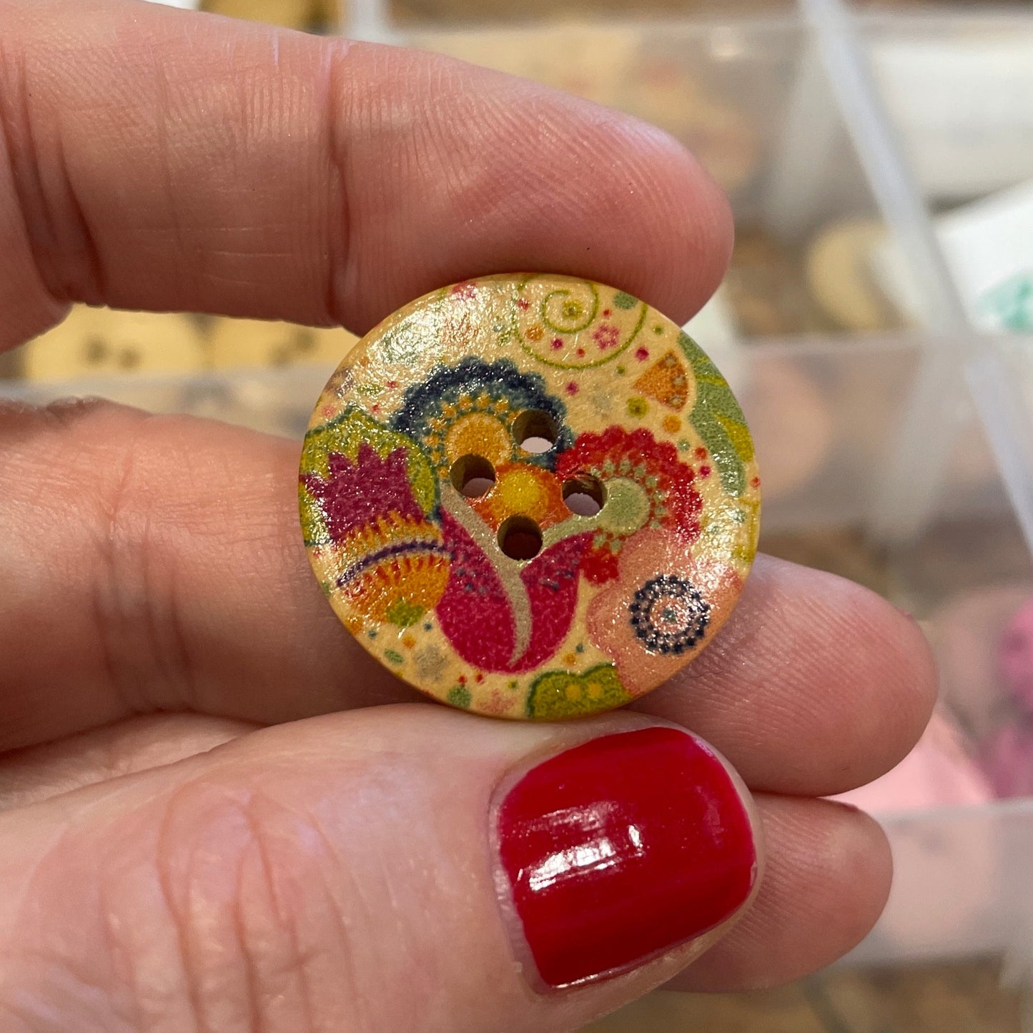 Colorful button held between fingers with a blurred background of buttons