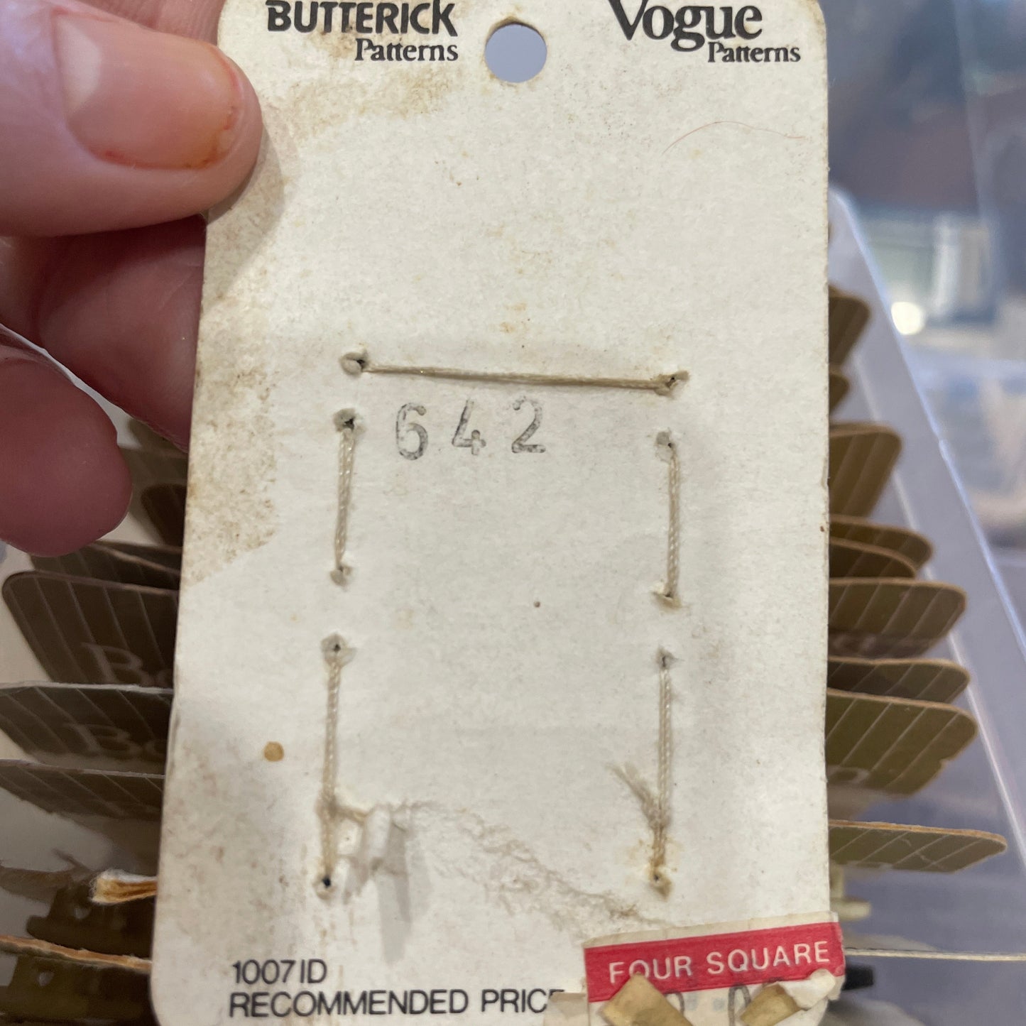 Vintage pattern card held by a hand with visible wear and tear.