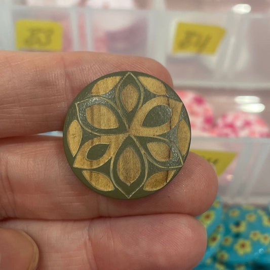 Hand holding a decorative button with a blurred background of button collection