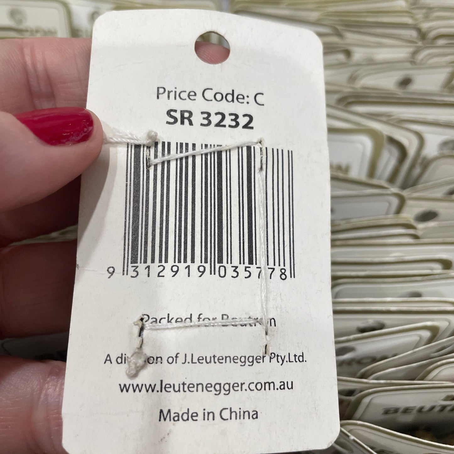 Close-up of a product tag with a barcode held by a hand.