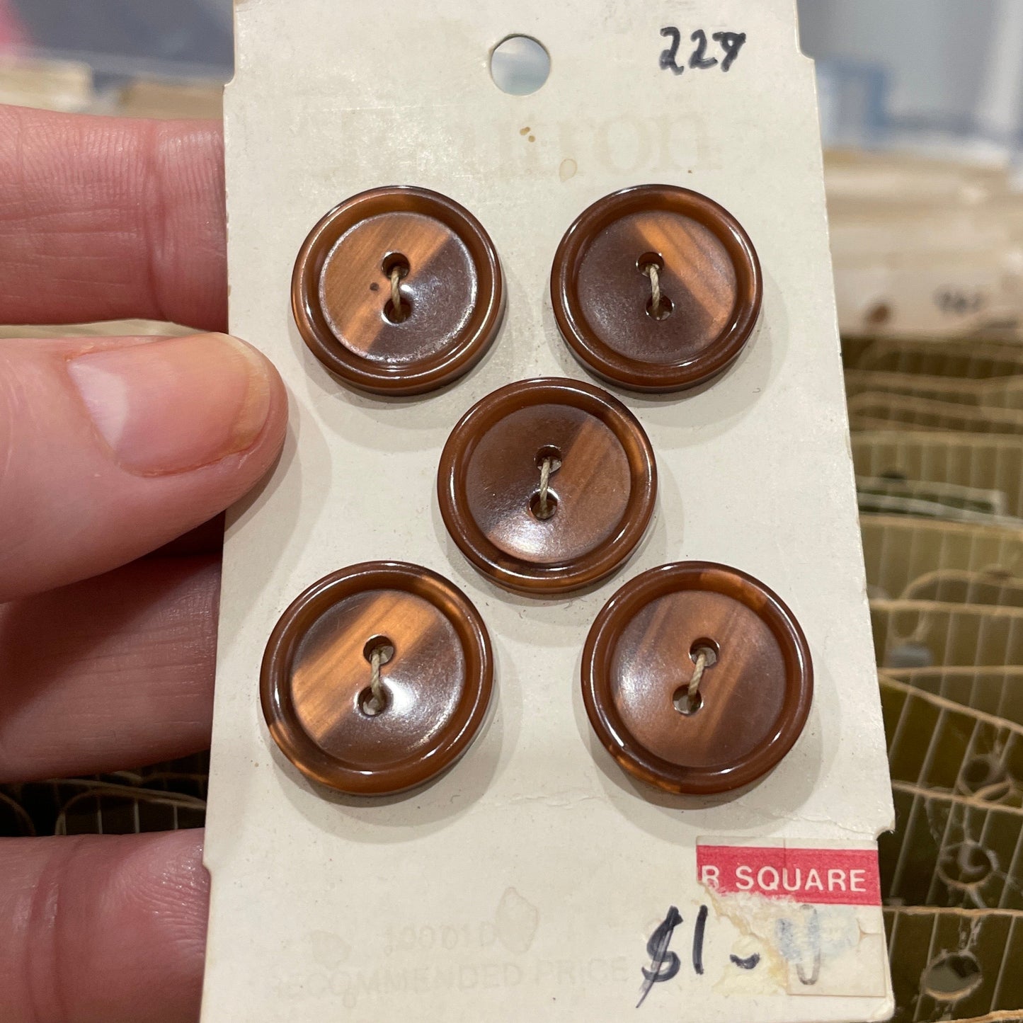Set of brown buttons on a card held by a hand with a blurred background