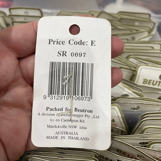 Close-up of a price tag held in a hand with blurred packaging in the background
