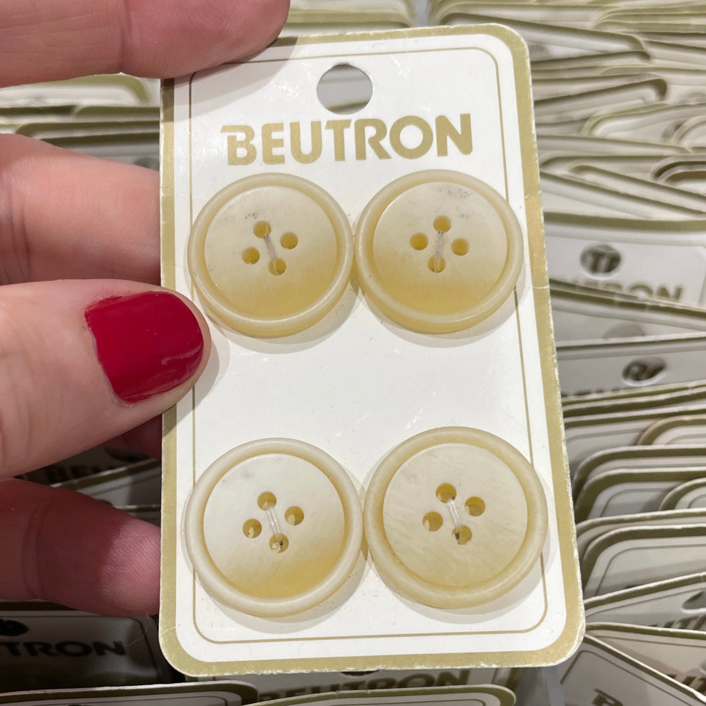 Hand holding a package of Beutron buttons with a blurred background