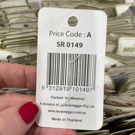 Hand holding a price tag with a barcode and text, with a background of similar items.