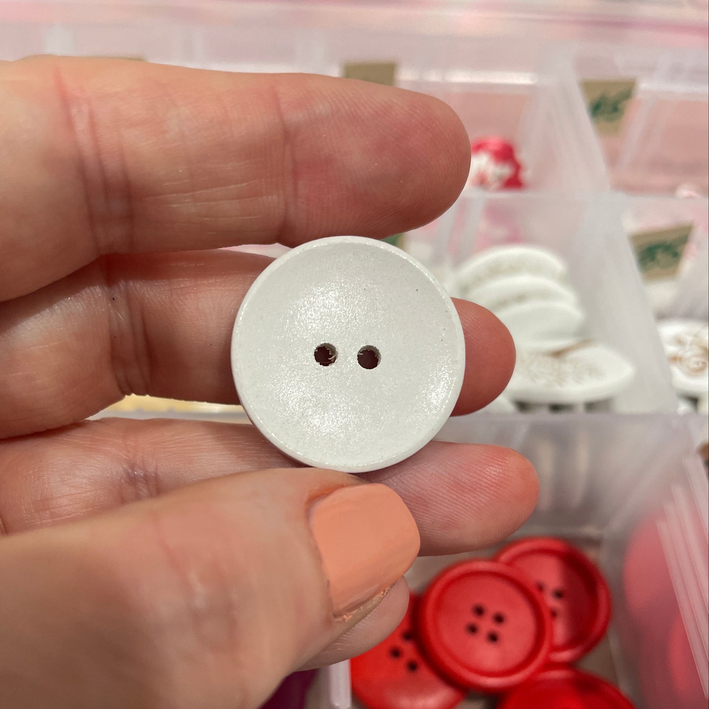 Hand holding a white button with a background of various buttons.