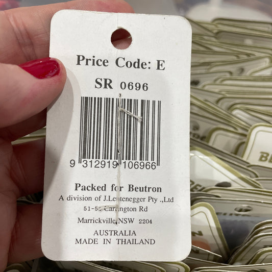 Close-up of a product tag with a barcode and text, held by a hand.