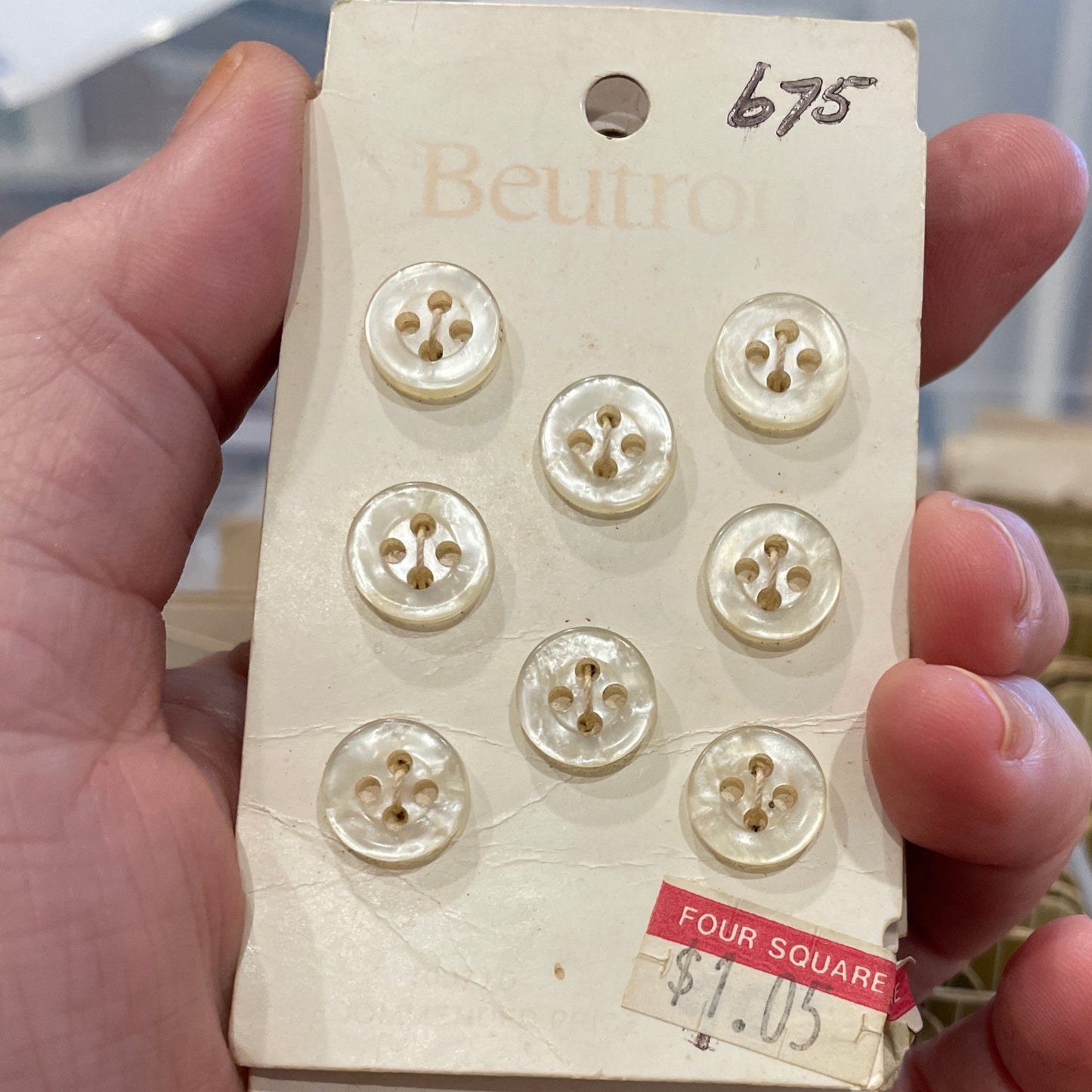 Hand holding a vintage button box with buttons on a blurred background