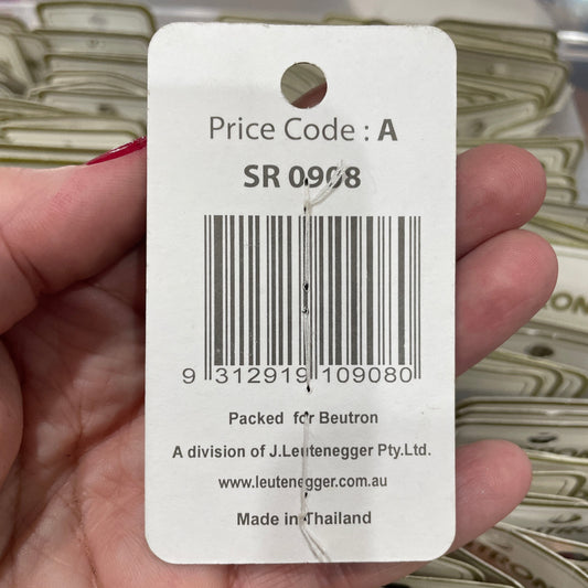 Product tag with barcode and text held by a hand against a blurred background
