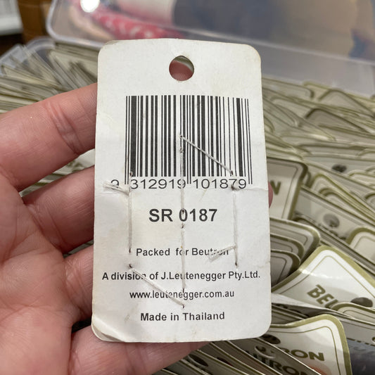 Hand holding a product tag with a barcode and text, with a blurred background of similar tags.