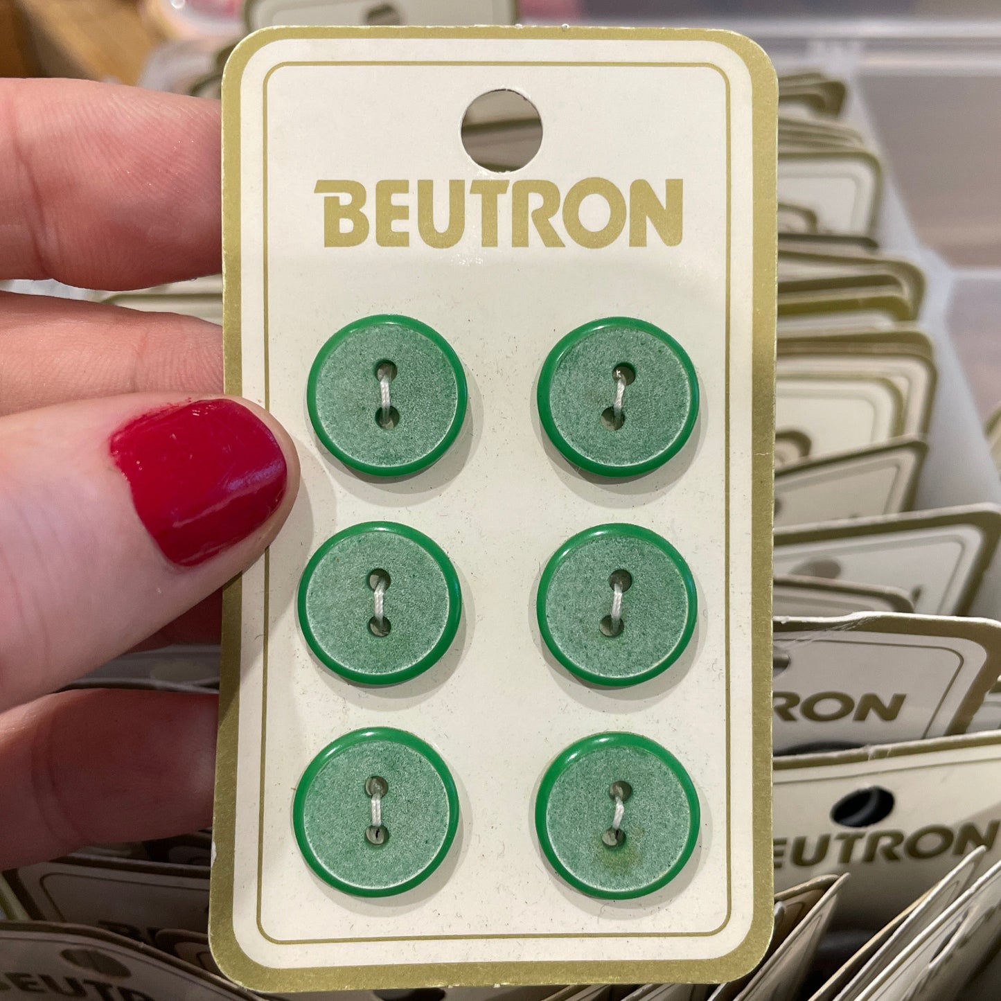 Hand holding a card with green buttons and 'Beutron' branding.