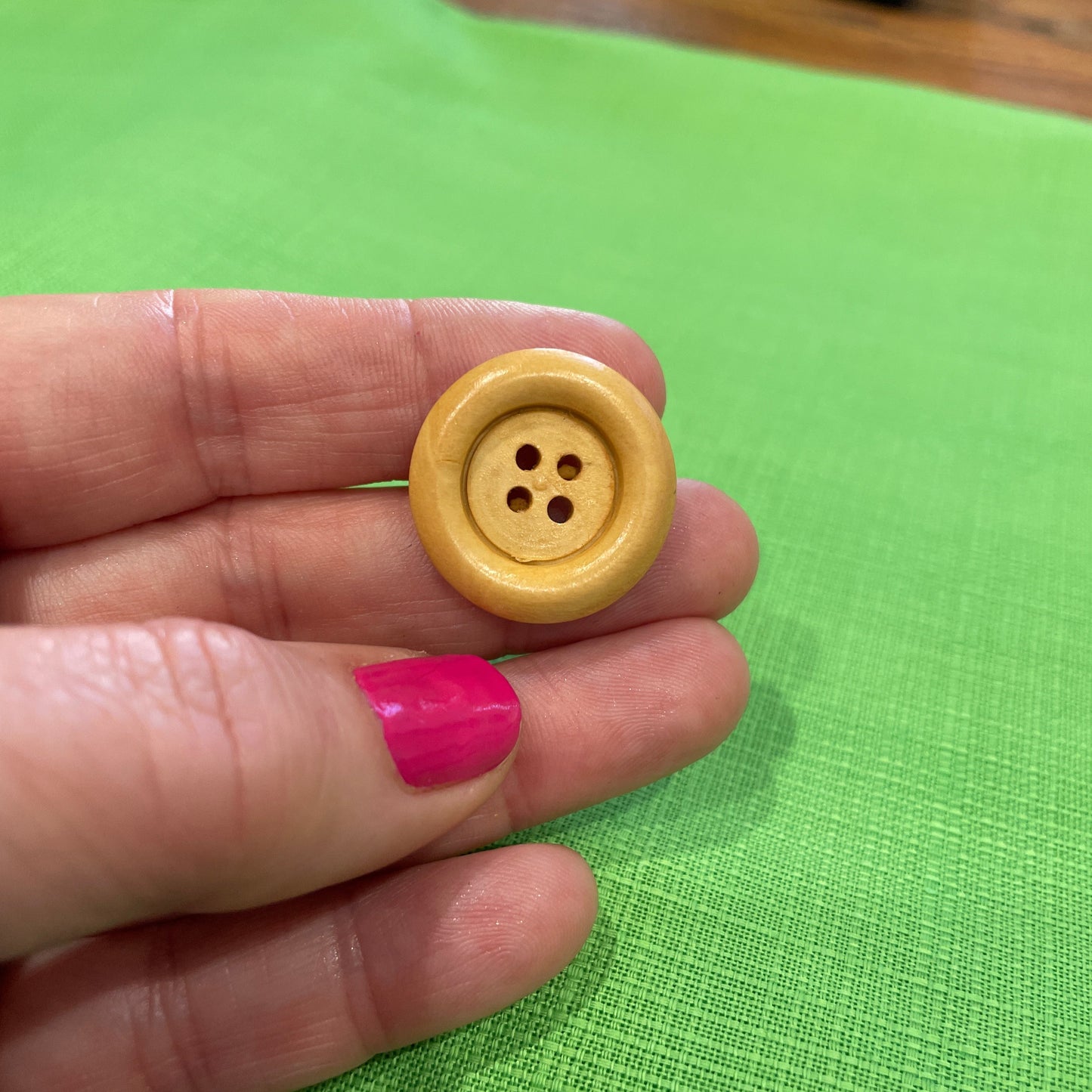 Hand holding a yellow button against a green background