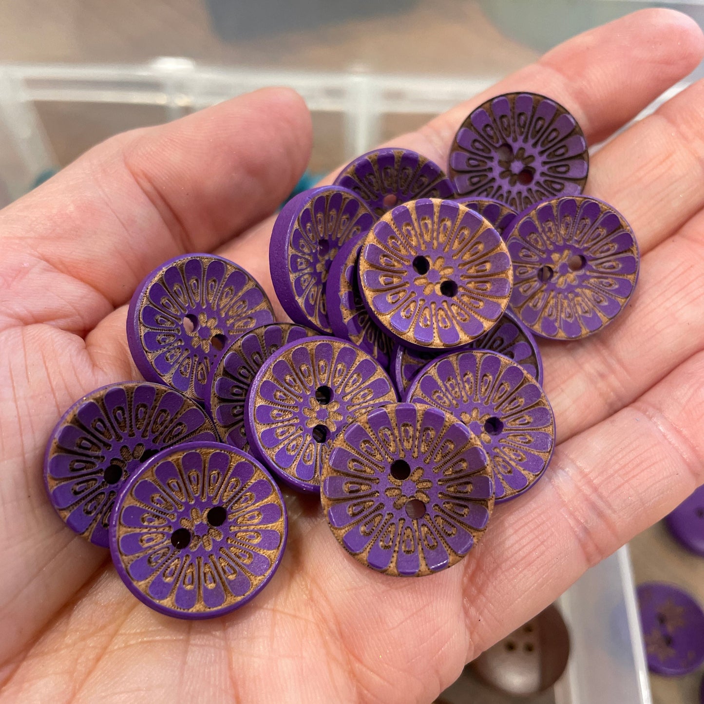 Hand holding purple buttons with gold patterns, blurred background