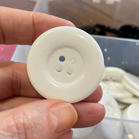 Hand holding a white button with a blurred background