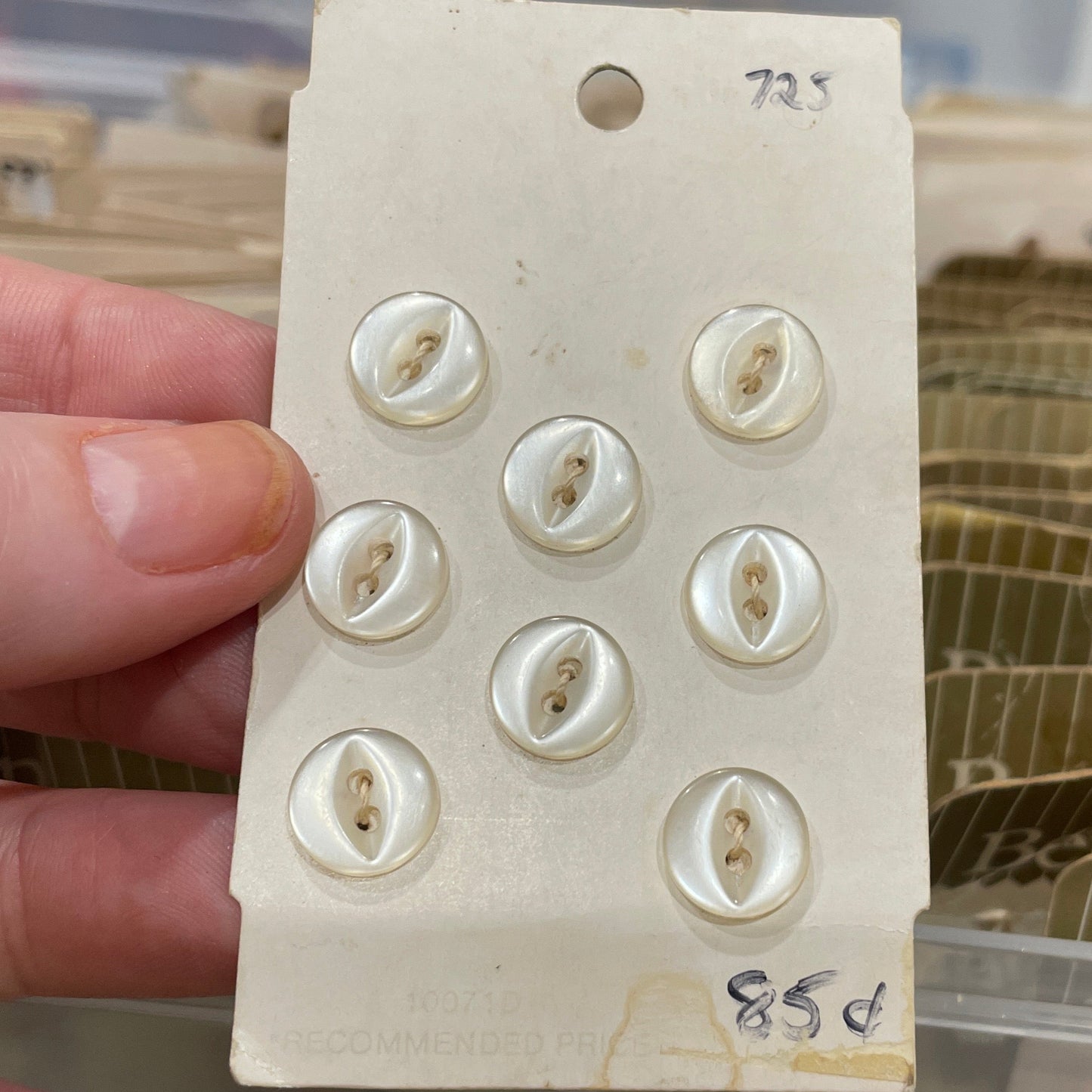 Card with buttons held by a hand against a blurred background of storage containers.