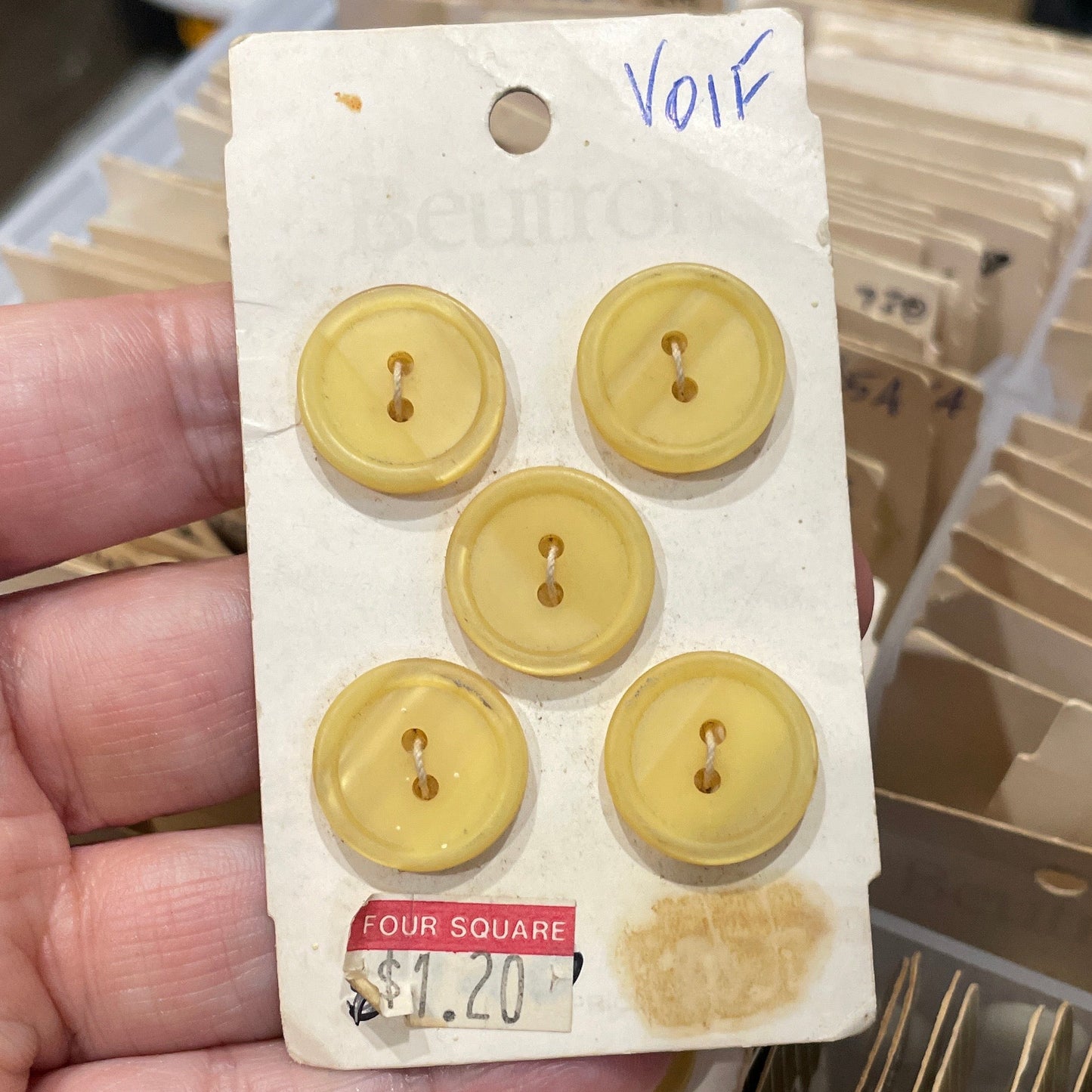 Hand holding a card with yellow buttons against a blurred background of similar cards.