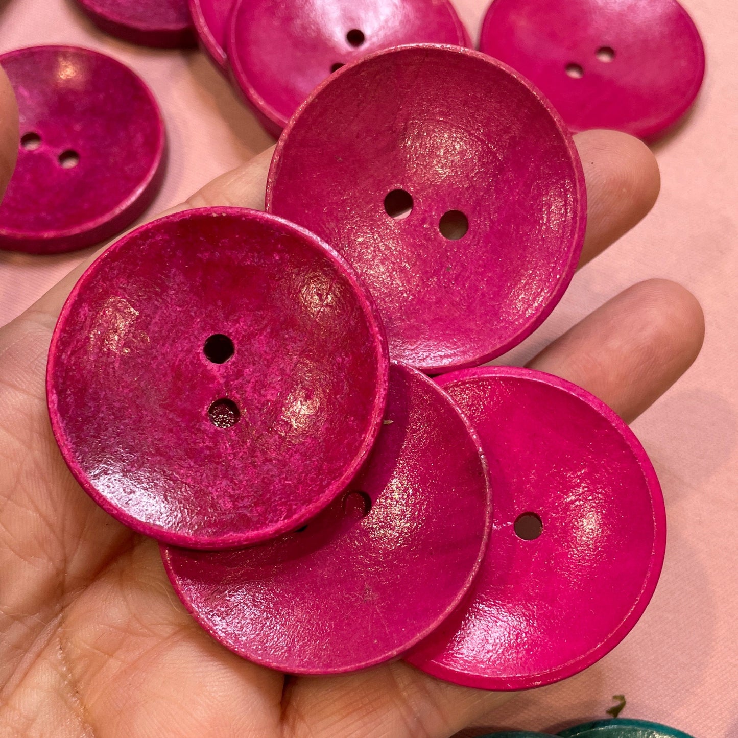 Hand holding pink buttons with a pink background