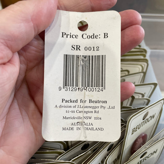 Hand holding a product tag with a barcode and text, surrounded by more tags.
