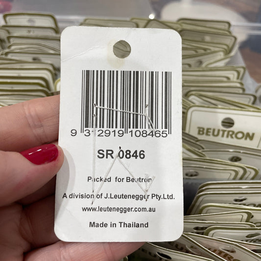 Barcode label held by a hand with red nail polish, with a blurred background of similar labels.