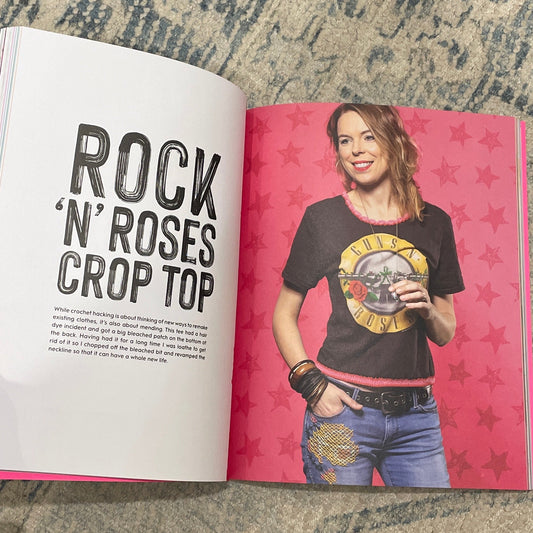 Open book on a textured surface with a person's hand holding it open.