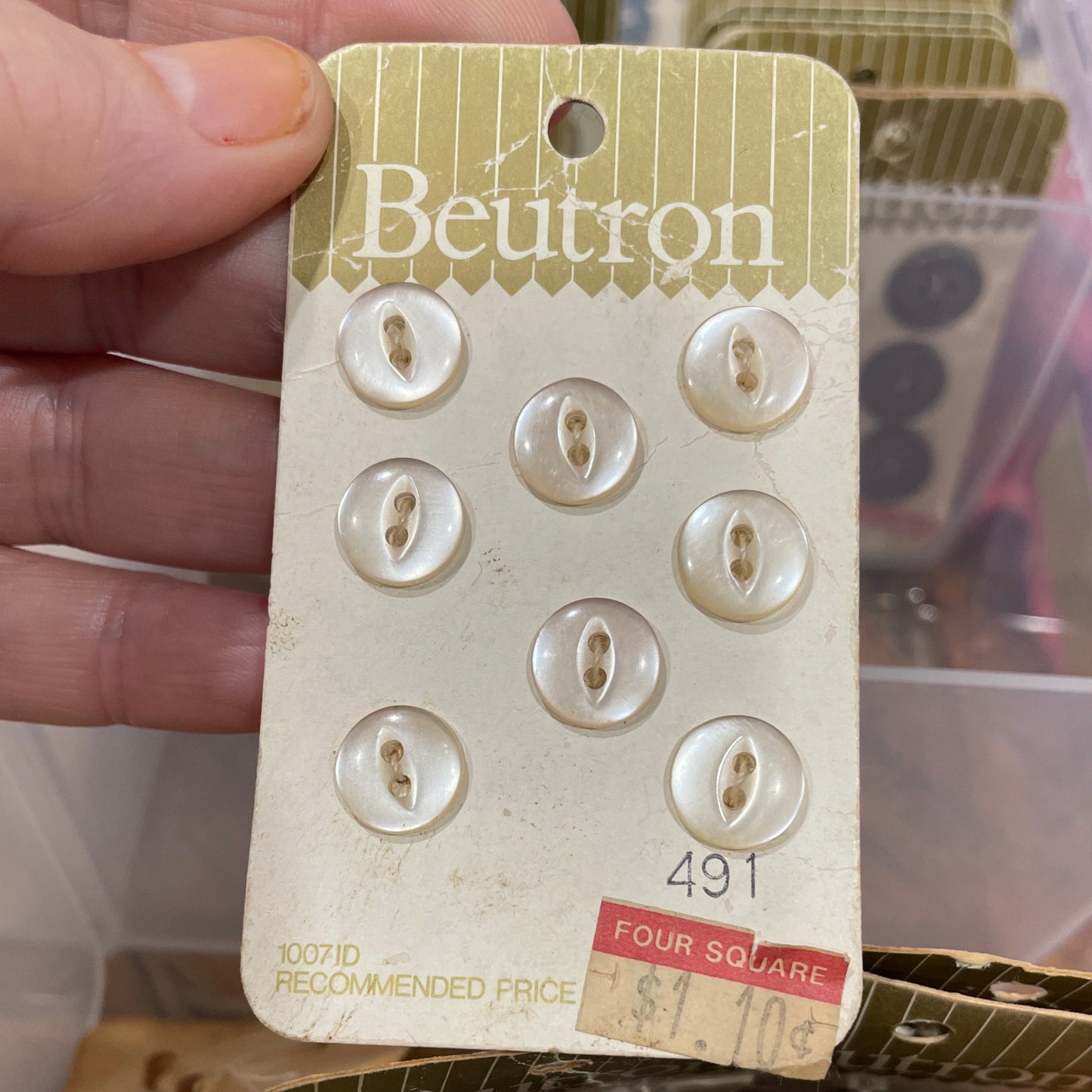Hand holding a package of buttons with 'Beutron' branding.