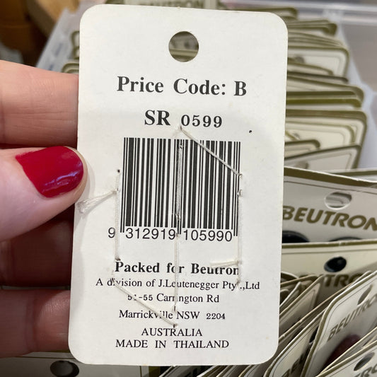 Close-up of a price tag with a barcode held by a hand, with multiple similar tags in the background.