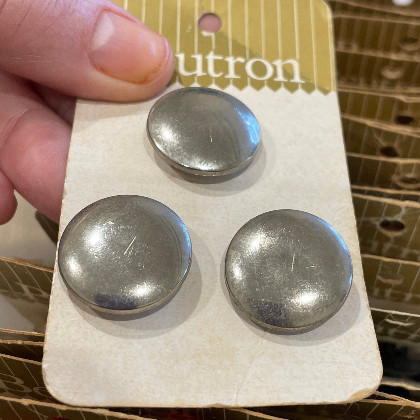 Hand holding a card with three metal buttons.