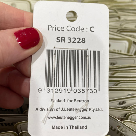 Hand holding a price tag with a barcode and product details, surrounded by more price tags.