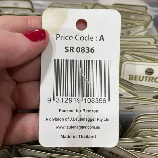 Hand holding a product tag with a barcode and text, with a blurred background of similar tags.