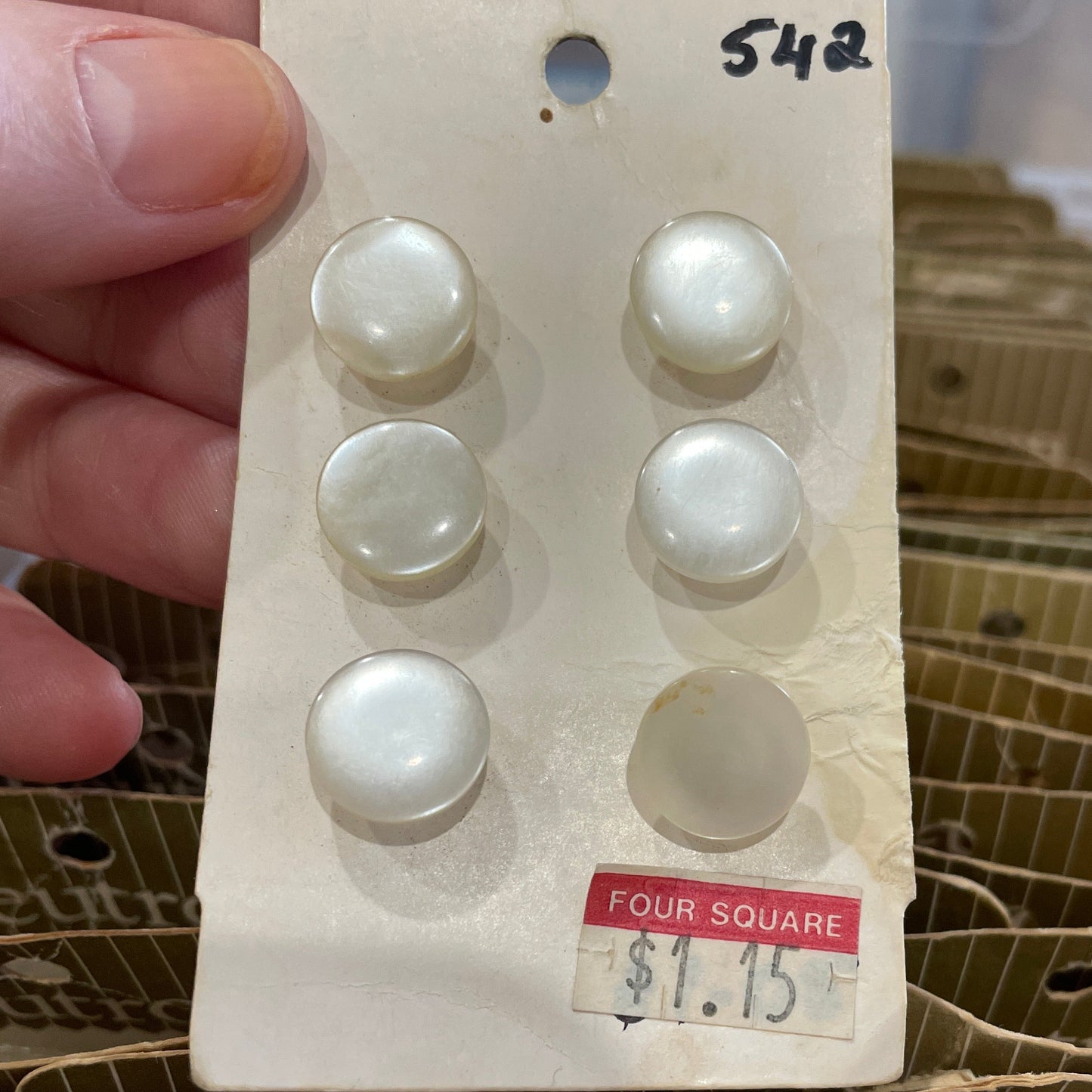 Set of pearl buttons on a card held by a hand with a blurred background