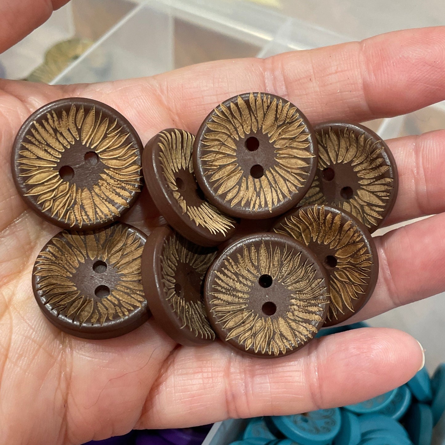 Hand holding brown buttons with a container of blue buttons in the background