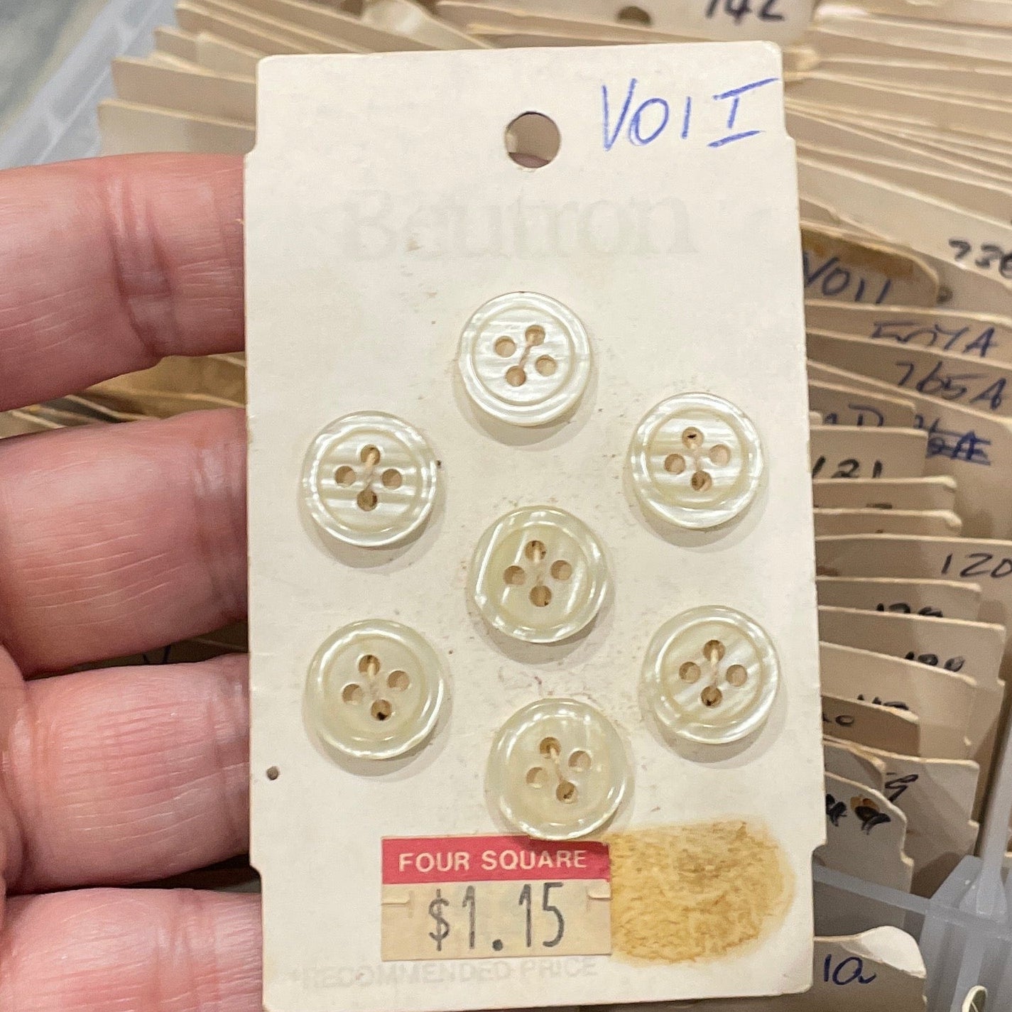 Hand holding a card with buttons against a background of similar cards.