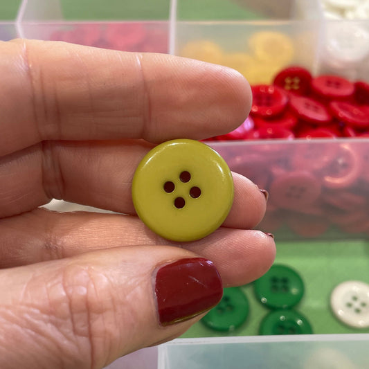 Hand holding a yellow button with a background of colorful buttons in clear containers