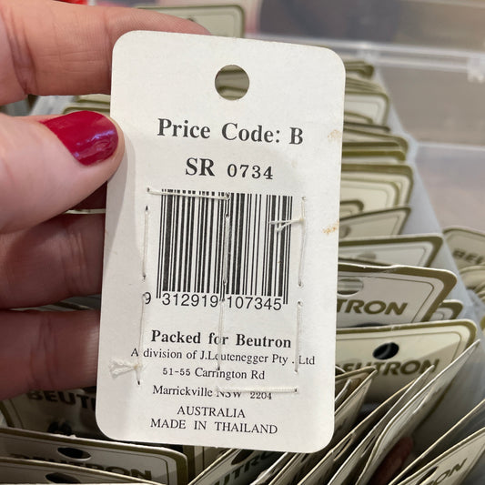 Close-up of a price tag with a barcode held by a hand, with more tags in the background.