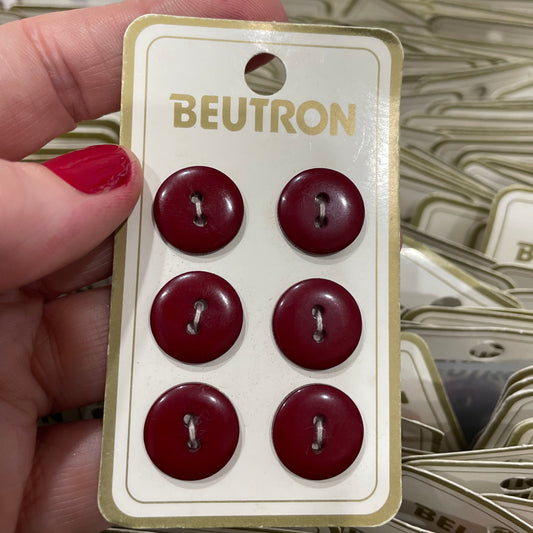 Card with six red buttons held by a hand, with 'Beutron' branding.